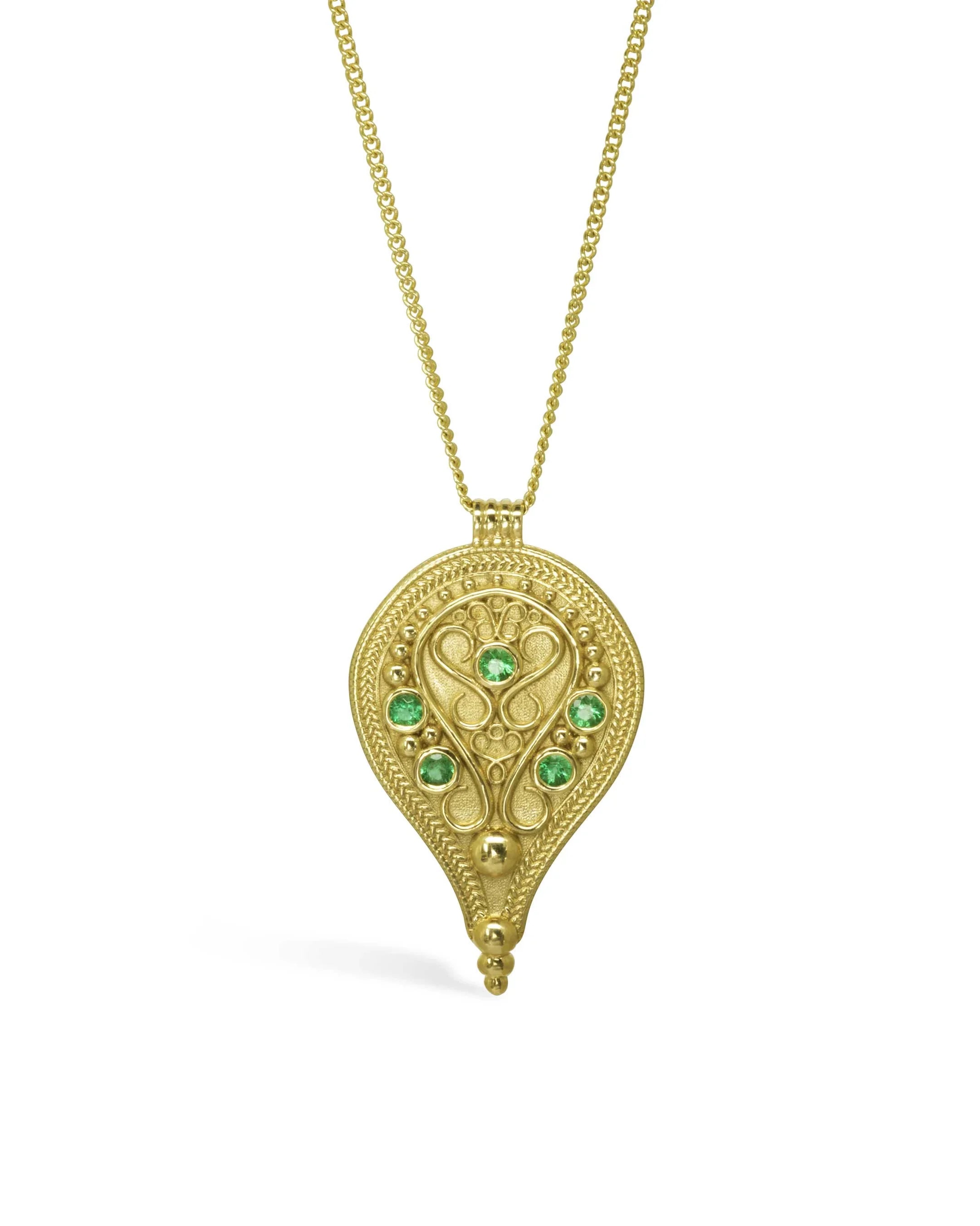 Gold filigree pendant necklace with green emerald gemstones on a white background