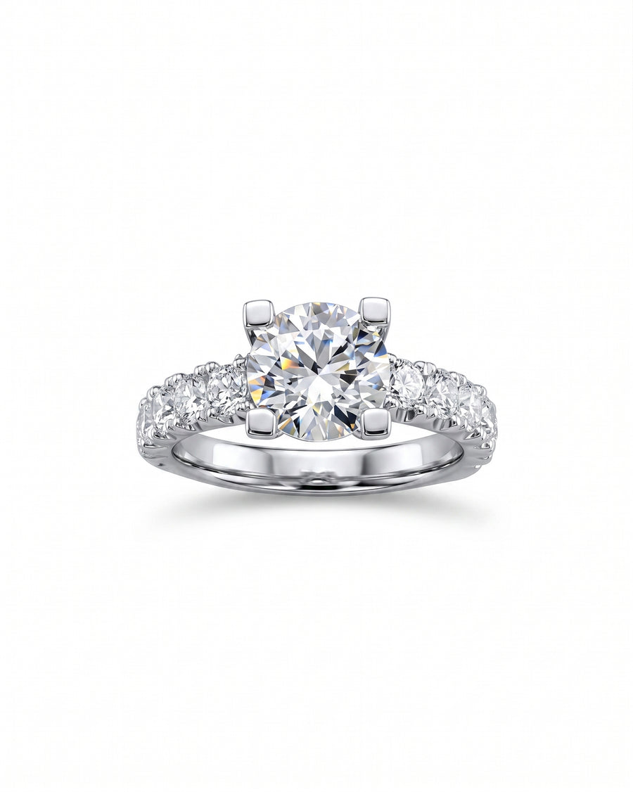 Silver fishtail set engagement ring with a round center diamond and pavé diamonds.