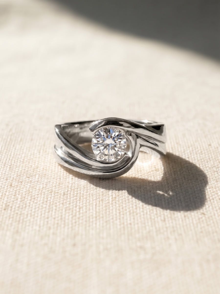 Platinum engagement ring with a round brilliant cut diamond set in a smooth, flat twist band design.