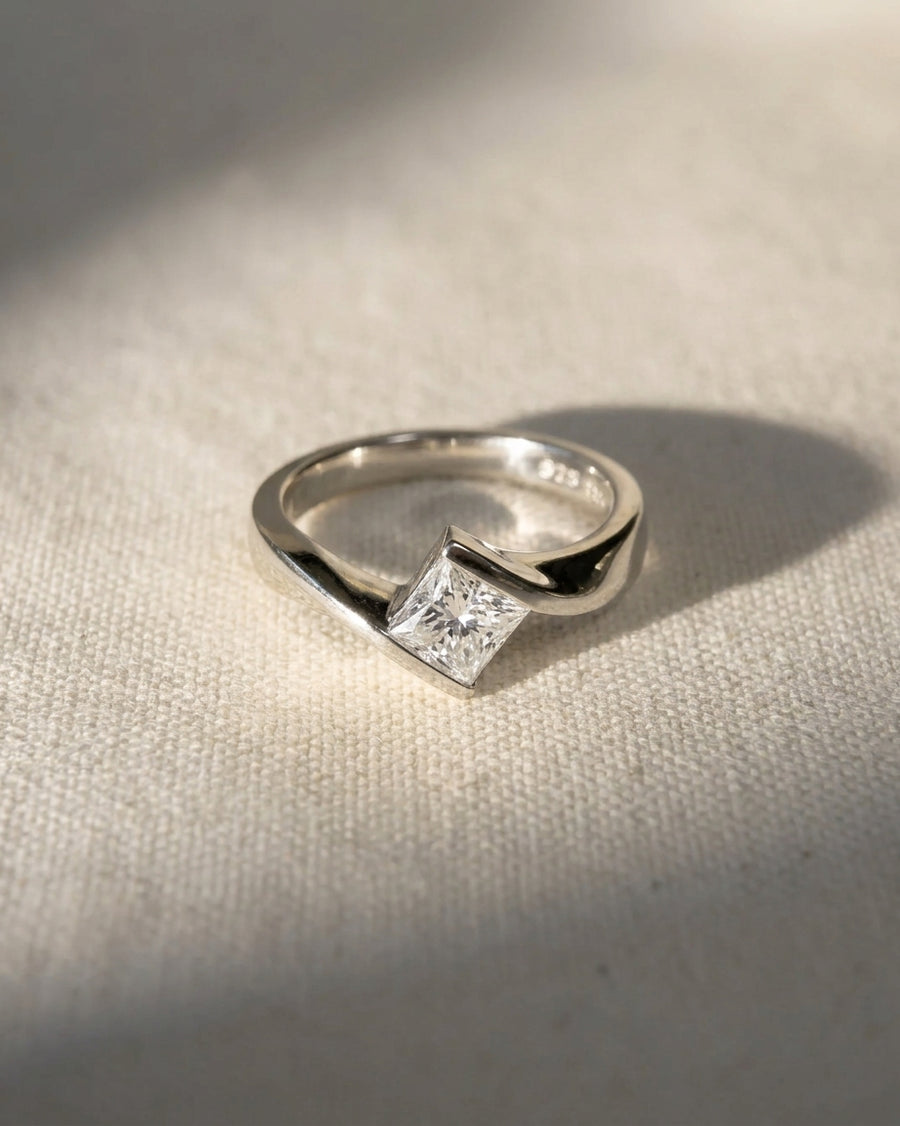 Yellow gold flat twist engagement ring with a princess cut diamond.