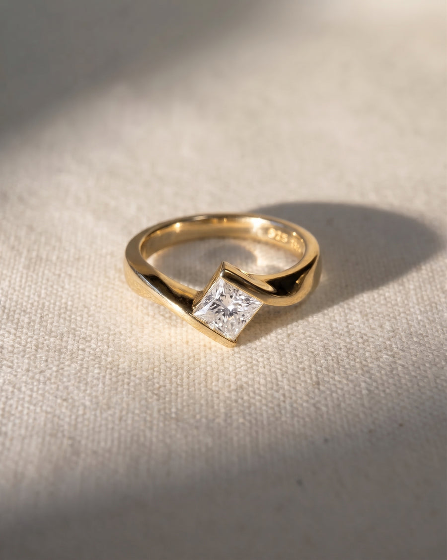 Gold flat twist engagement ring with a princess cut diamond.