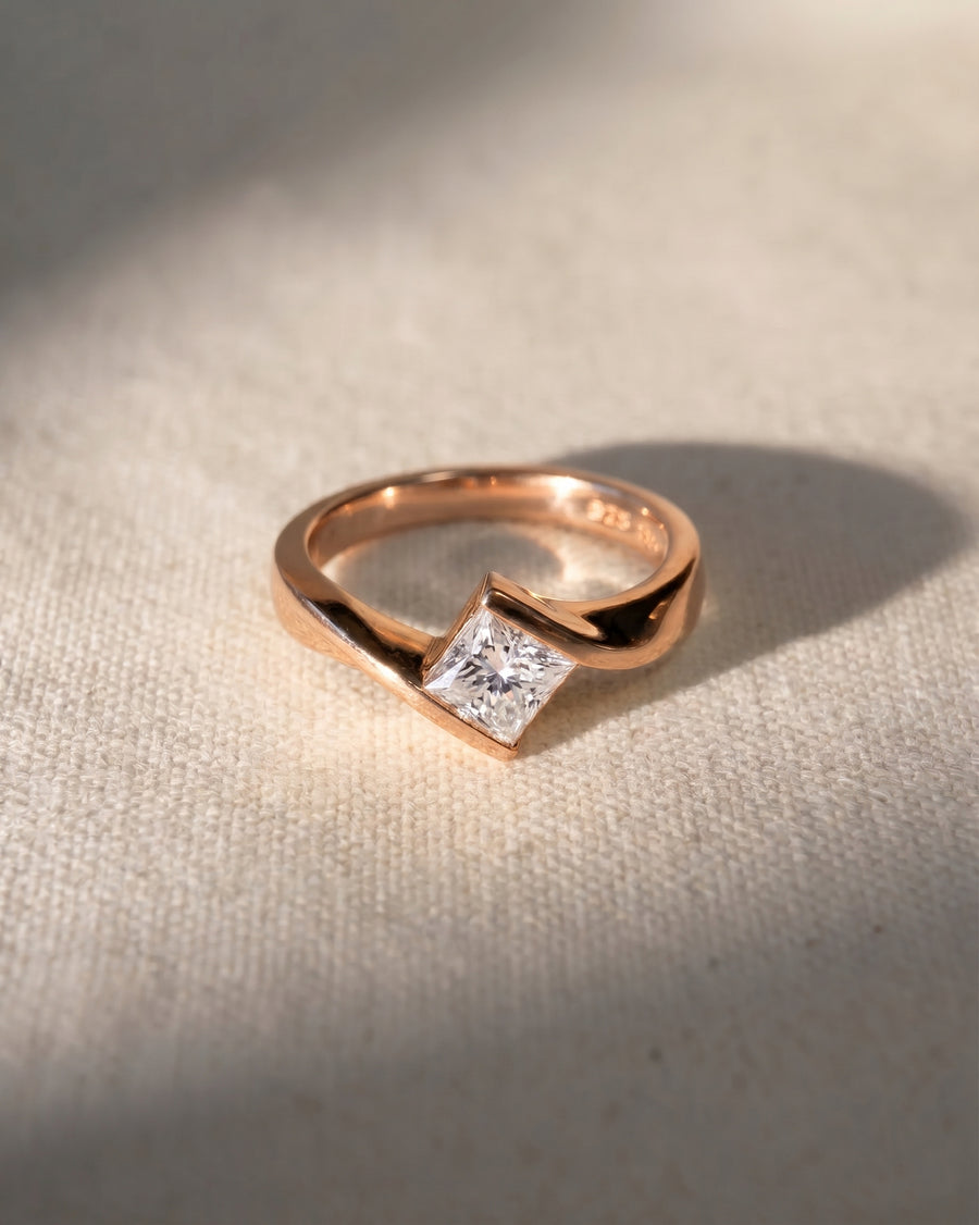 Rose gold flat twist engagement ring with a princess cut diamond.