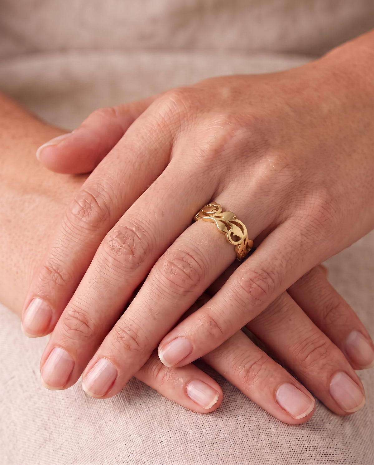 9ct rose gold floral ring with an openwork leaf design worn on a finger.