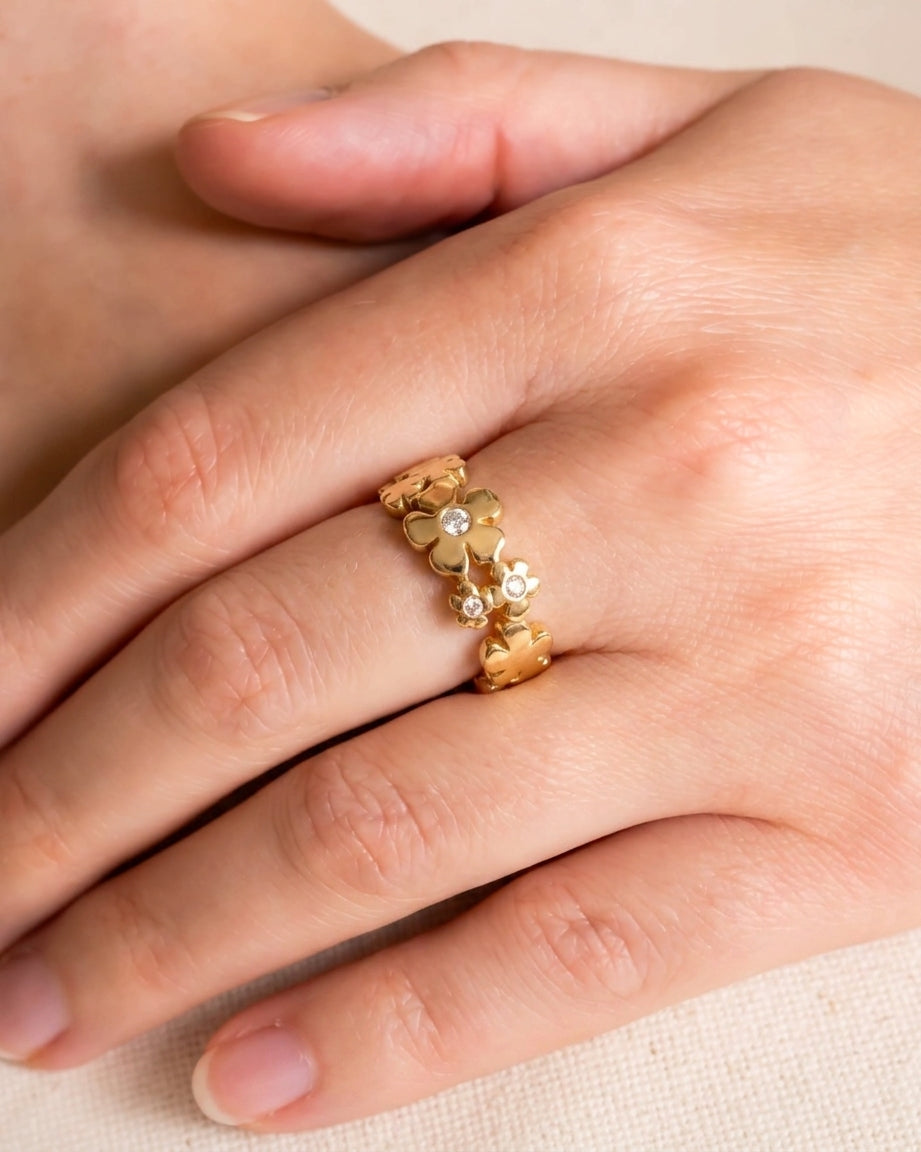 Gold flower eternity ring with diamonds on a hand.