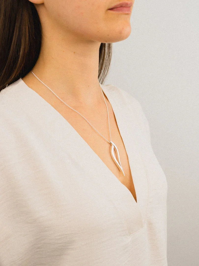 Woman wearing handcrafted silver pendant necklace with organic shape, minimalist style