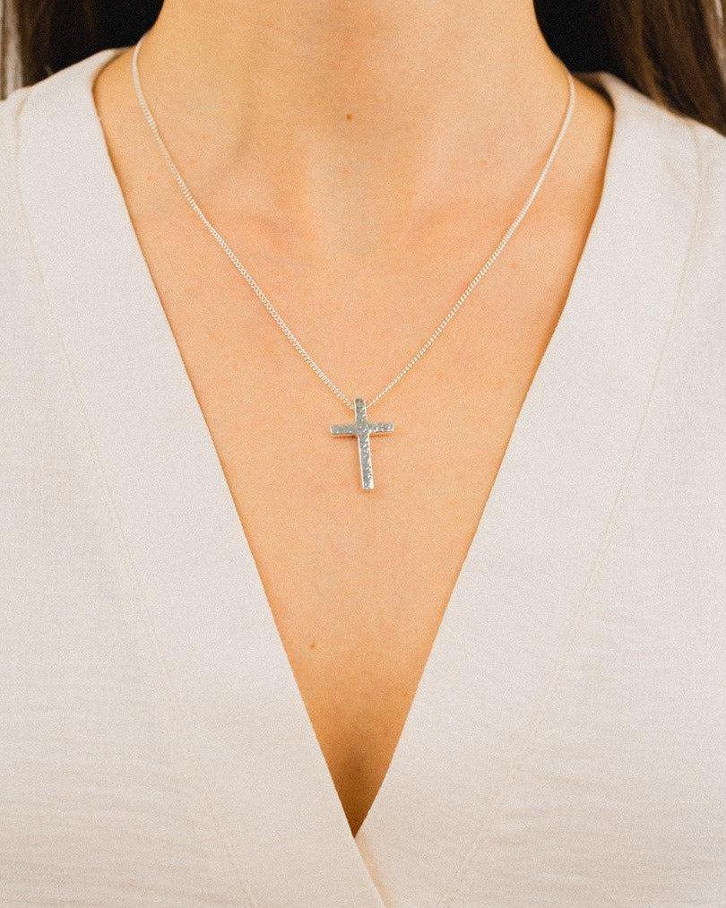 Forged solid silver cross pendant with a textured finish on a silver chain.