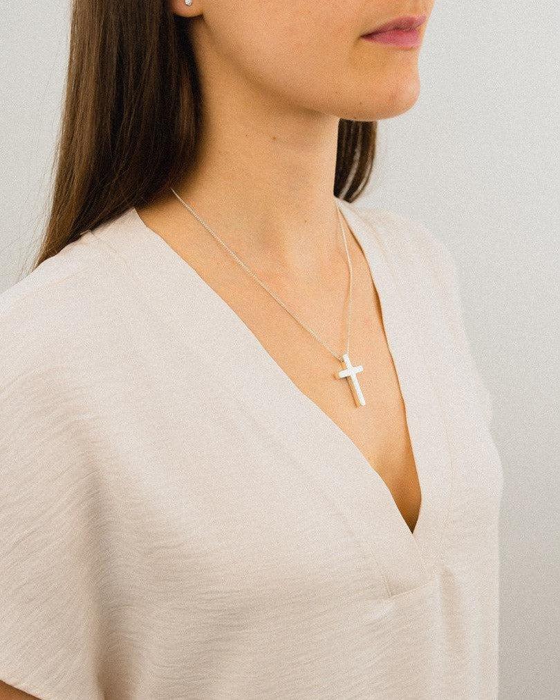Solid silver cross pendant with straight sides and bail on a chain.