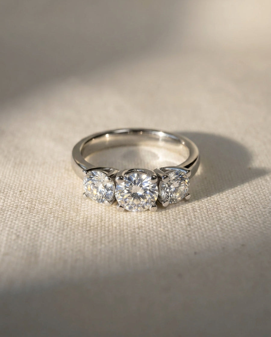 Platinum trilogy ring featuring three round brilliant cut diamonds in a four-claw setting.