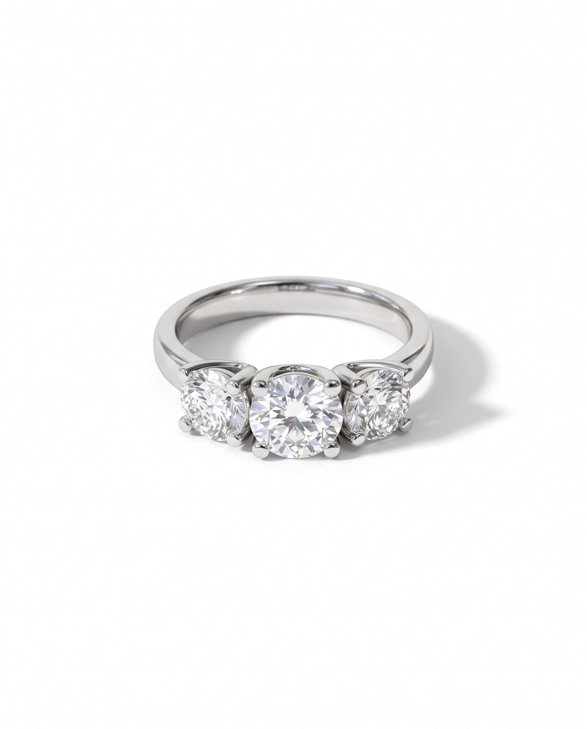 Platinum trilogy ring featuring three round brilliant diamonds in four-claw settings on a polished band.