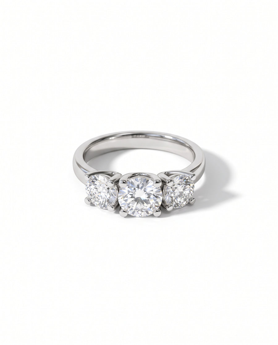 Platinum trilogy ring featuring three round brilliant diamonds in four-claw settings on a polished band.