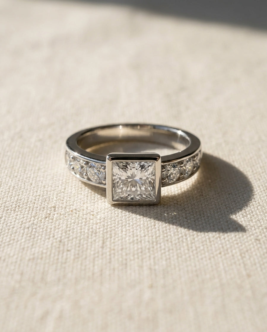 White gold engagement ring with a princess cut diamond and channel set diamonds.