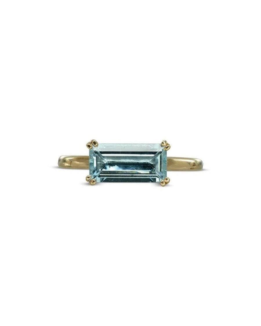 Gold ring with a light blue baguette-cut gemstone.