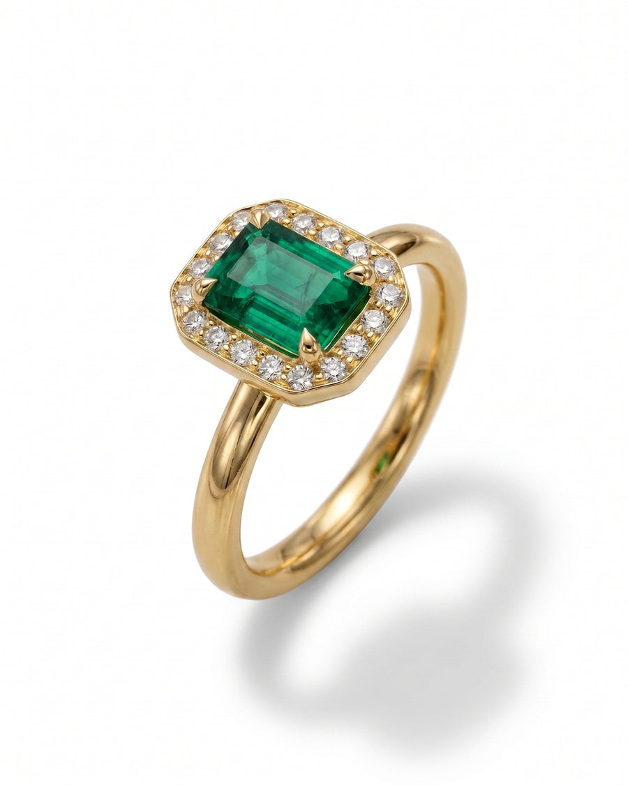 Gold ring with an emerald-cut emerald surrounded by diamonds.