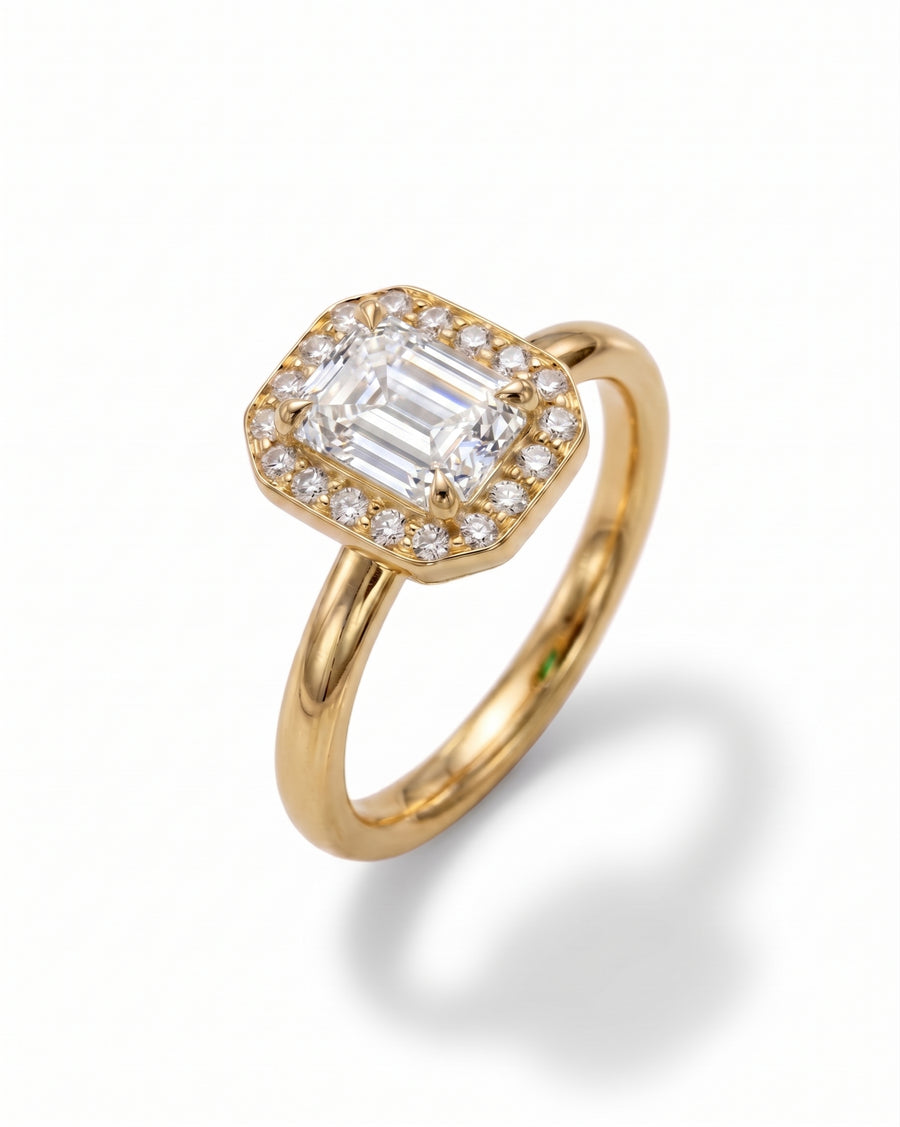 Gold engagement ring with an emerald-cut diamond surrounded by smaller round diamonds.
