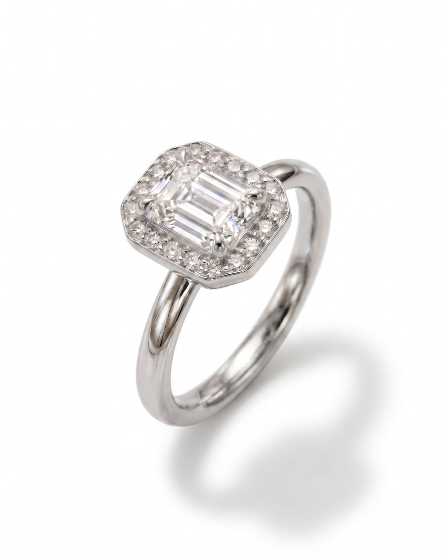 Platinum engagement ring with an emerald-cut diamond surrounded by smaller diamonds.
