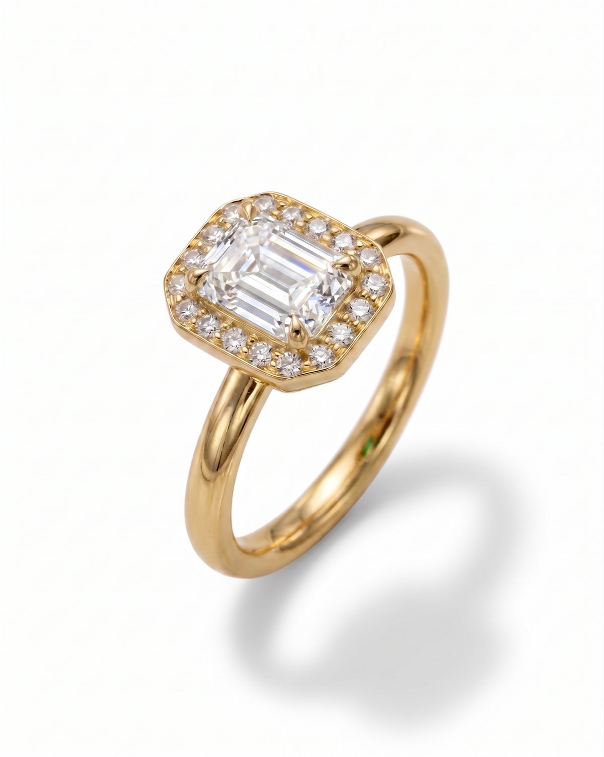 Gold engagement ring featuring an emerald-cut center diamond surrounded by a halo of smaller round diamonds.
