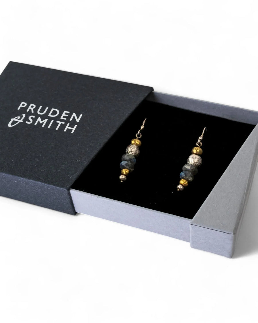 Drop earrings featuring gold and silver nuggets with faceted grey gemstones in a black presentation box.
