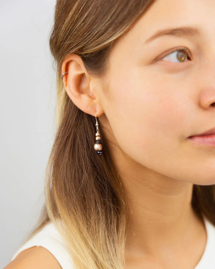 Silver and gold nugget drop earrings featuring deep red garnet gemstones worn on a woman's ear.