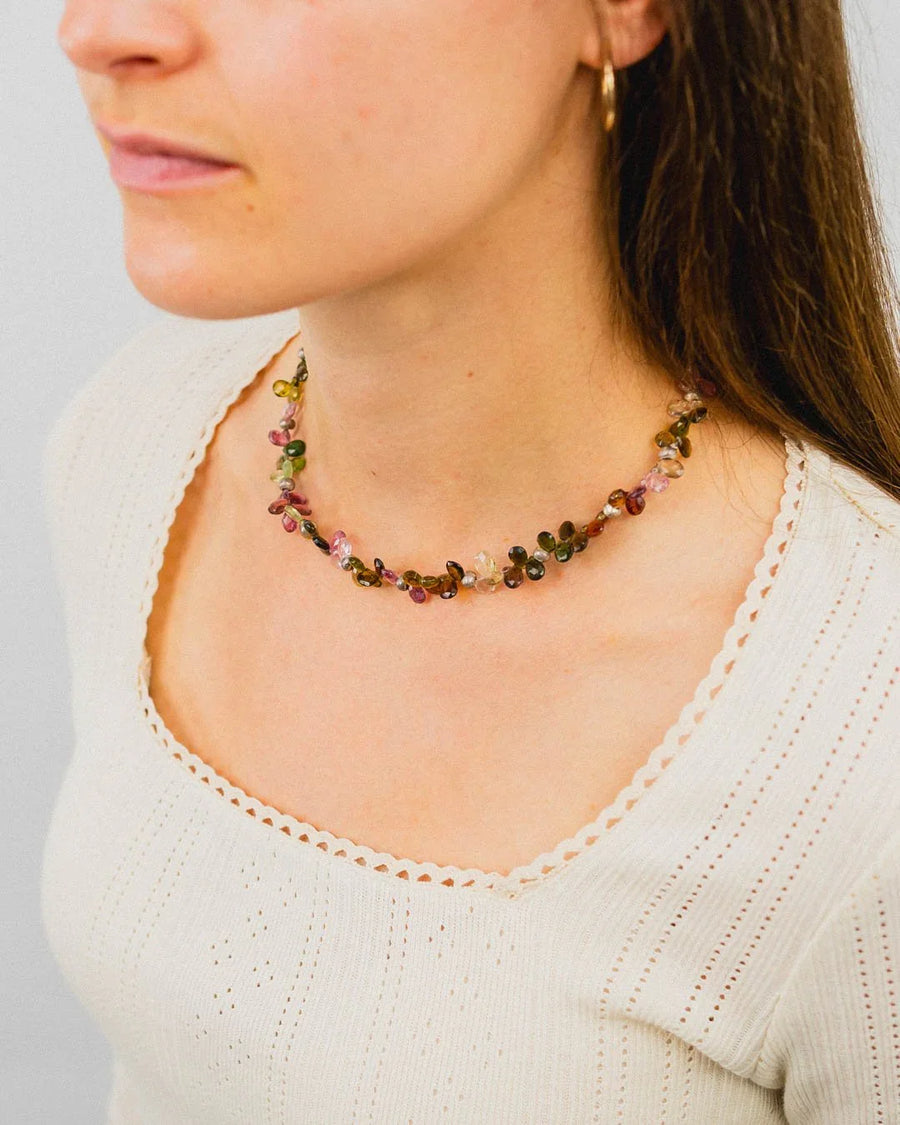 Woman wearing a teardrop gemstone necklace with multicoloured stones, handmade jewellery