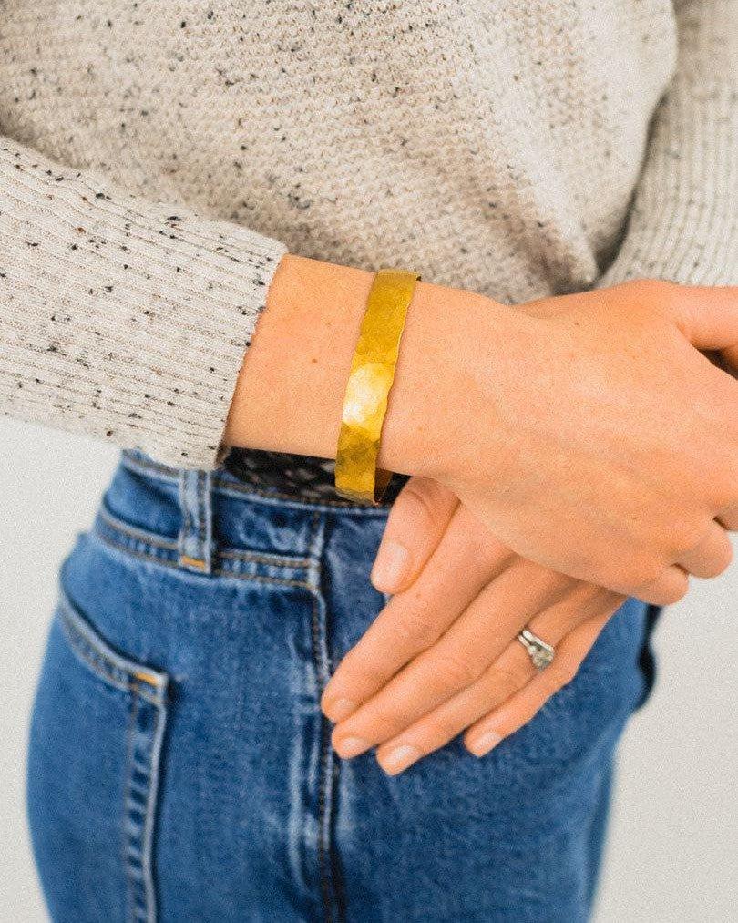 Handcrafted 9ct gold hammered bangle with matte finish on wrist, paired with casual outfit