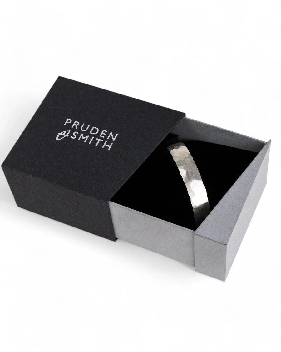 Hammered matte solid gold bangle with textured edge in a black jewelry box