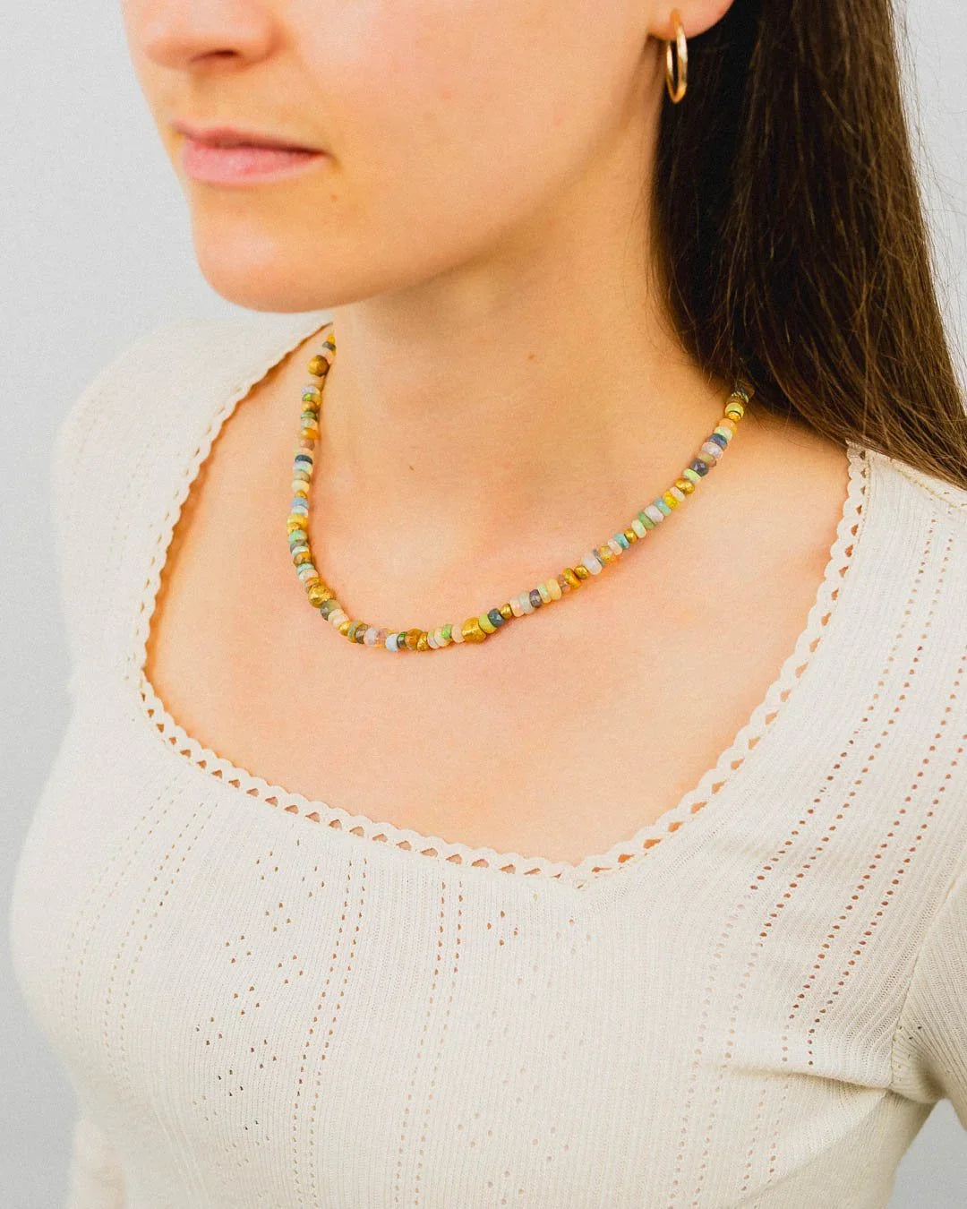 Woman wearing a natural gold nugget opal beaded necklace with organic shapes