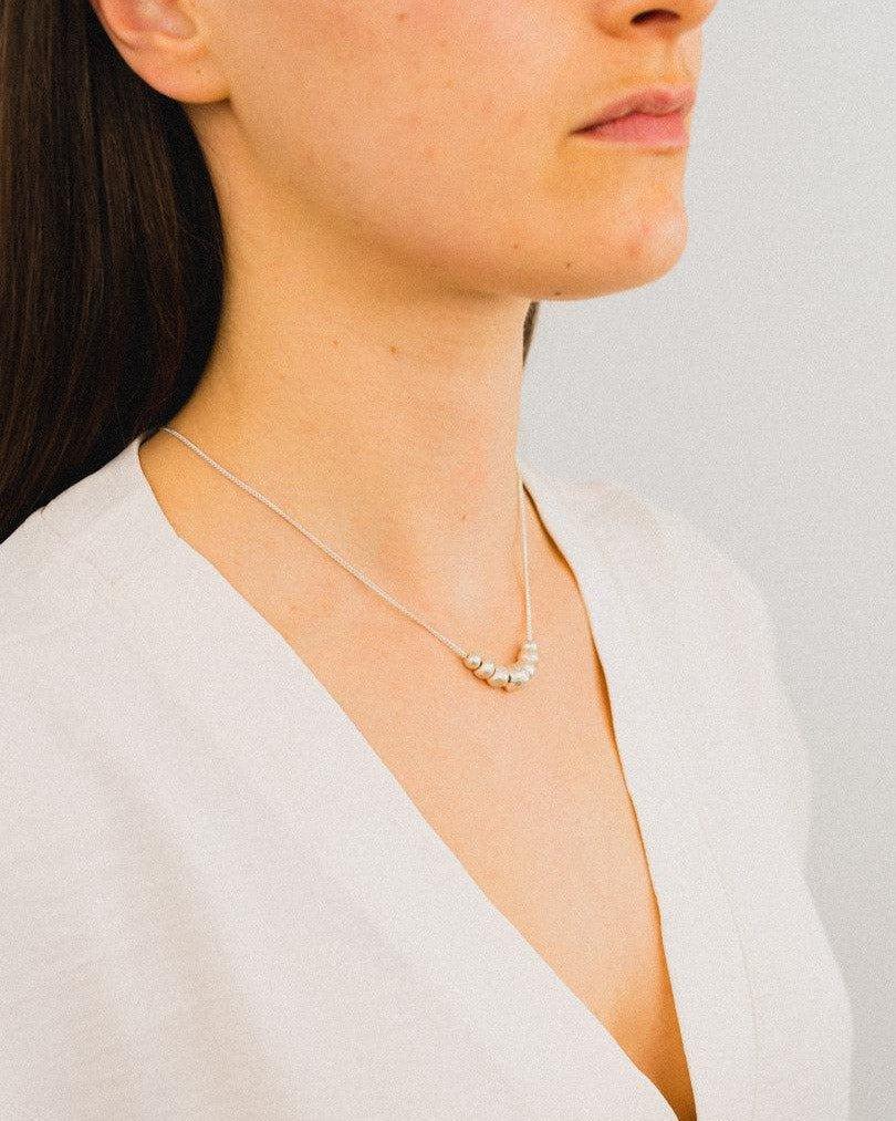 Woman wearing a delicate silver nugget necklace on a fine chain