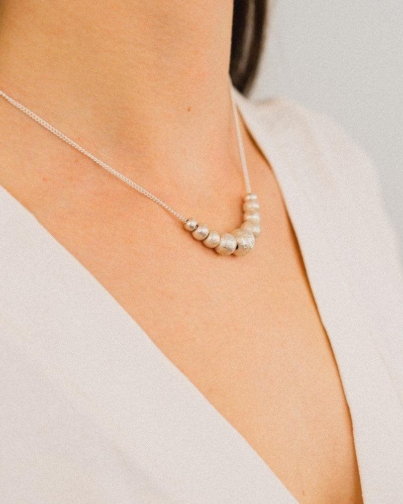 Handmade silver nugget necklace with organic shapes on a delicate chain, worn on neck