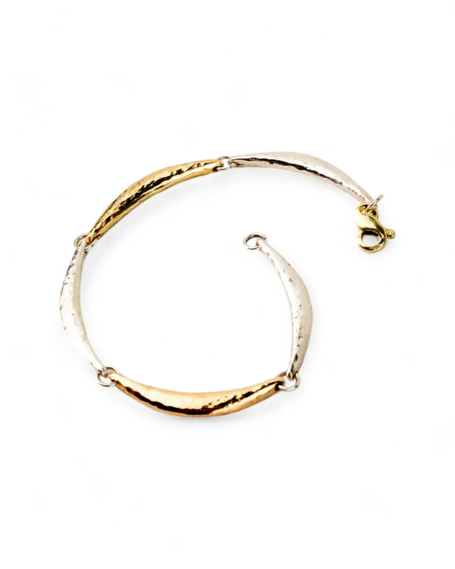 Hammered silver and gold crescent bracelet with a textured finish on a white background