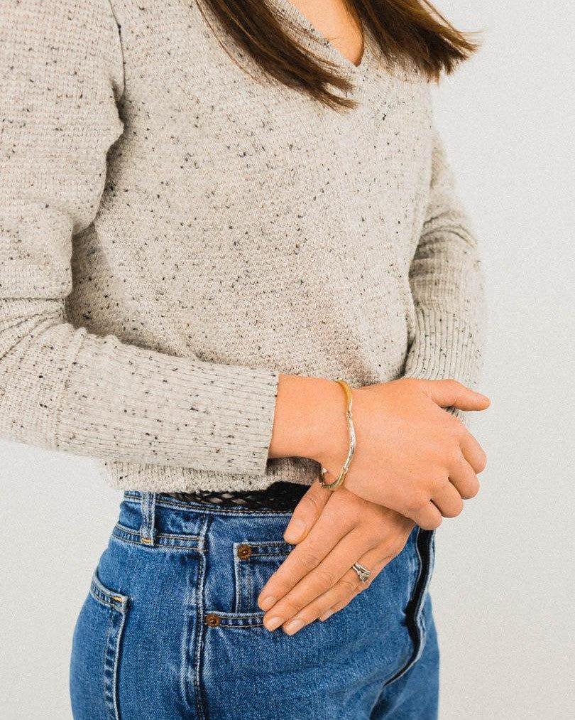 Woman wearing hammered crescent silver and gold bracelet with casual outfit
