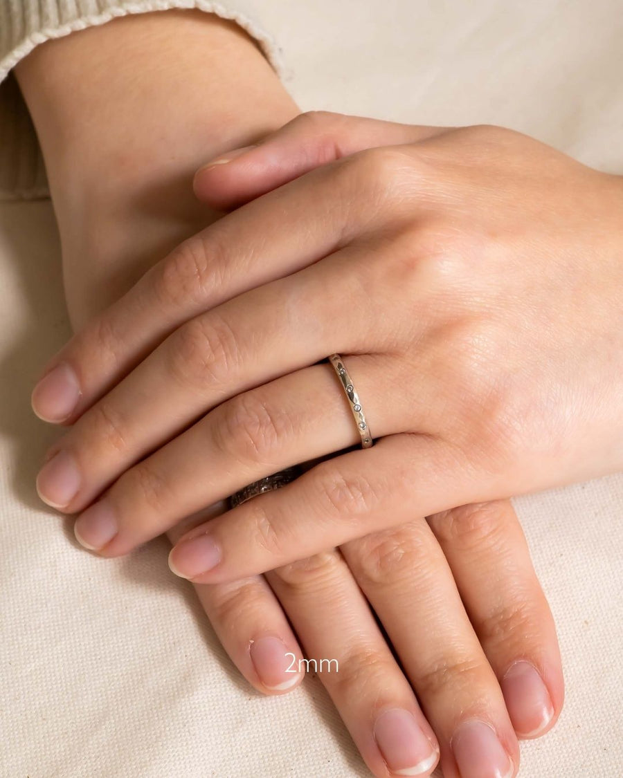 Silver hammered diamond ring on a hand, 2mm wide.