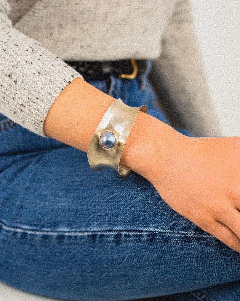 Hammered silver cuff bangle with a single round blue gemstone.