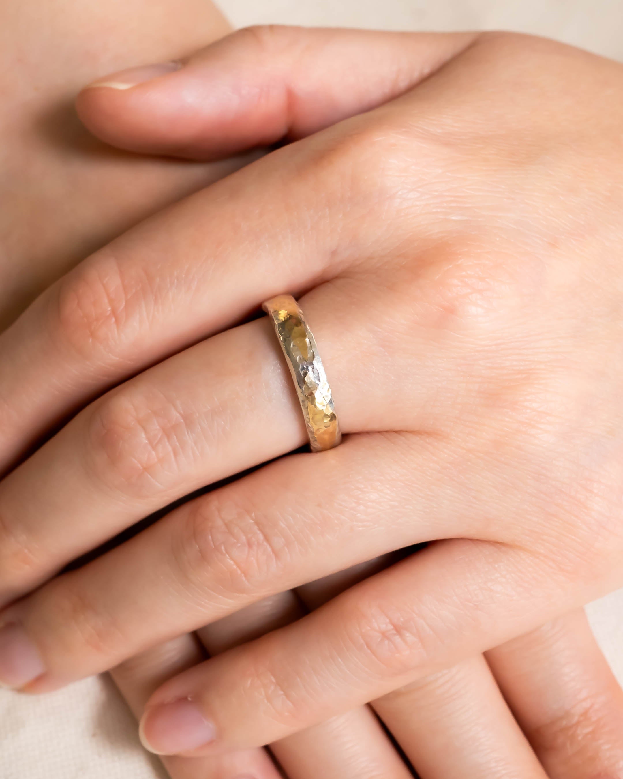 Hammered mixed metal court ring with a small gemstone on a hand.