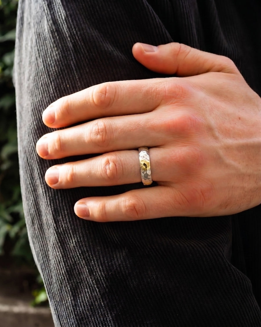 Hammered mixed metal court ring with a yellow gemstone on a man's finger.