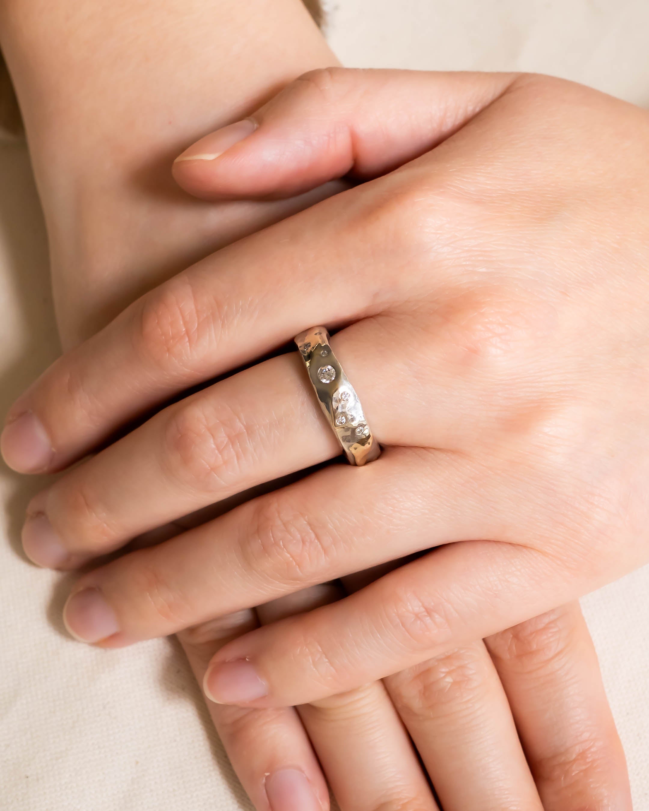 Hammered mixed metal gold diamond ring on a hand.
