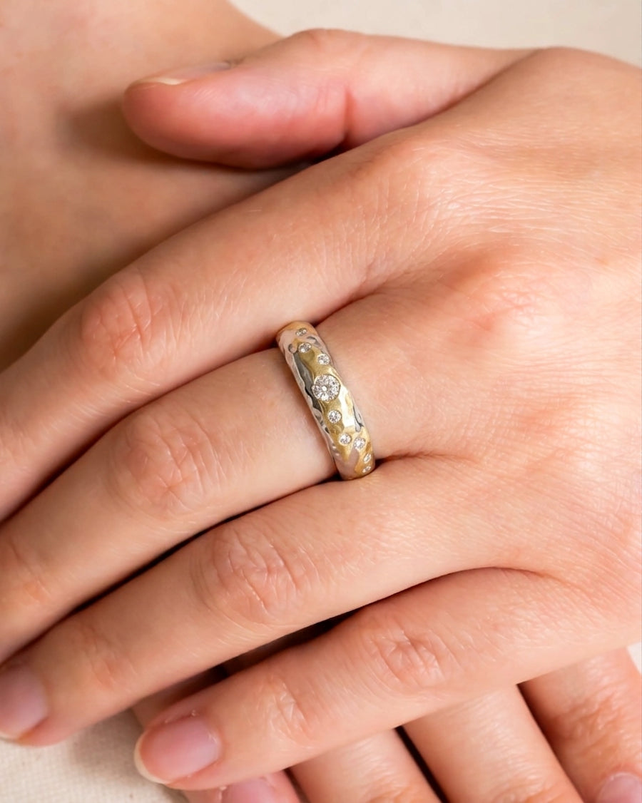 Hammered mixed metal gold diamond ring on a hand.
