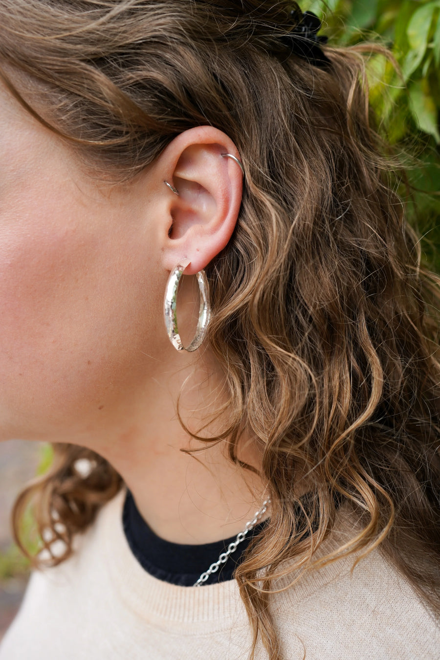 9ct white gold hammered rough hoop earring on an ear.