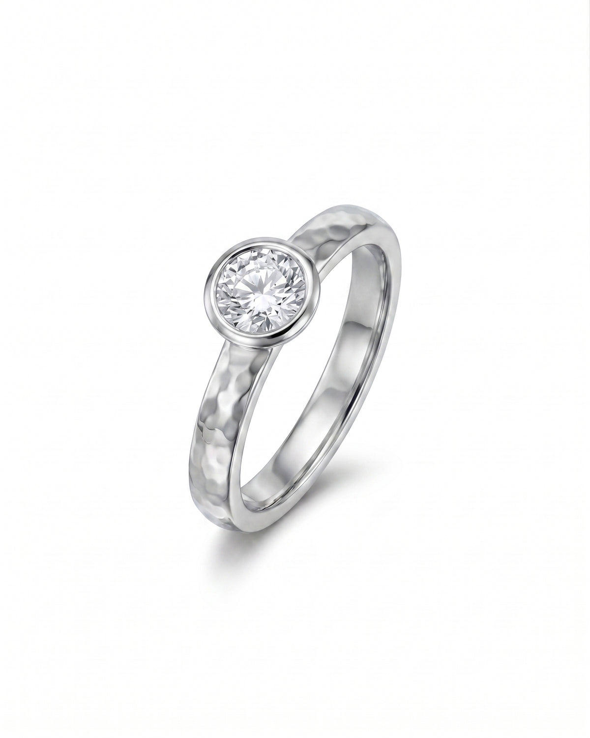 Platinum ring featuring a round brilliant cut diamond in a bezel setting on a hammered silver band.