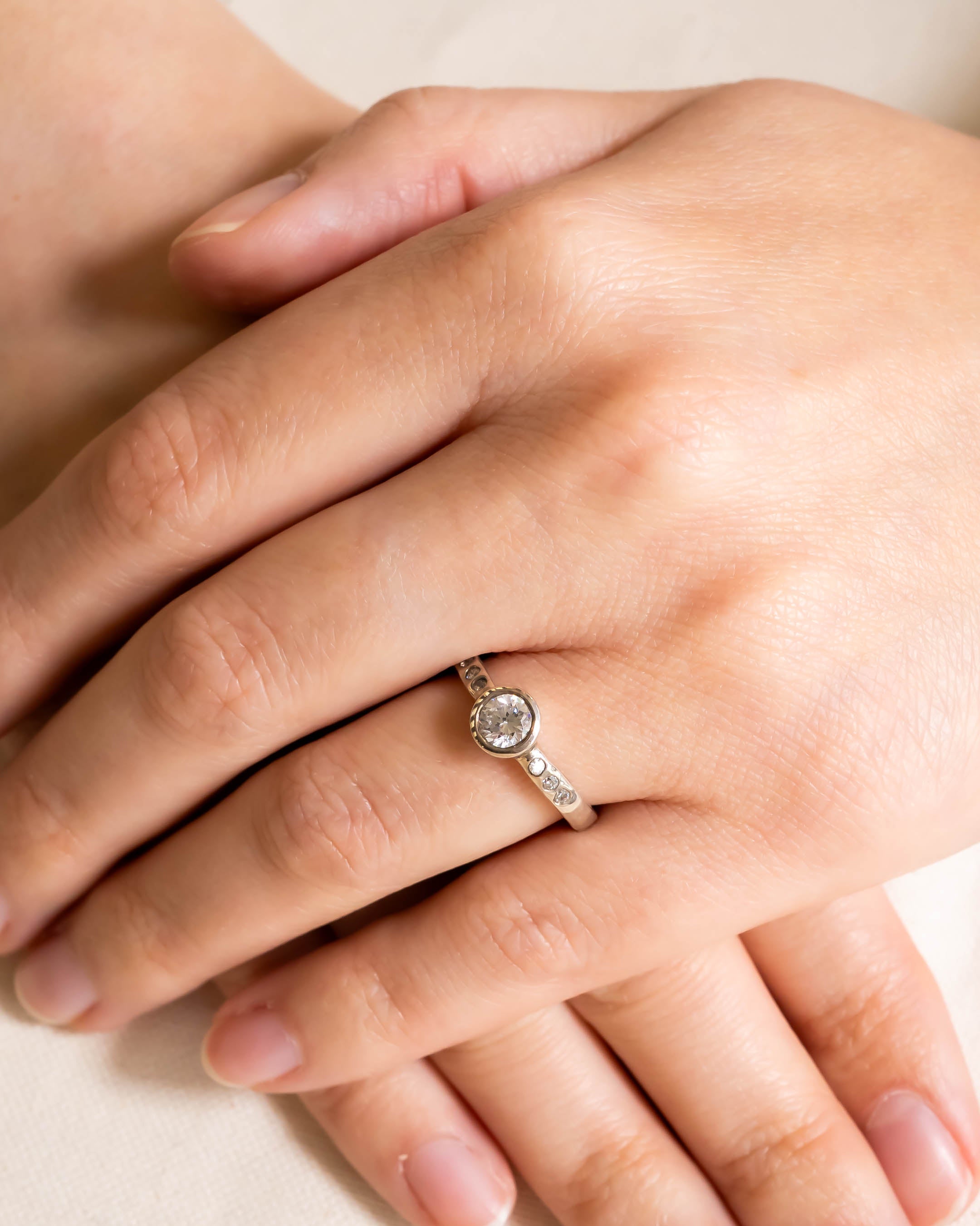 Platinum hammered round brilliant cut diamond ring on a hand.
