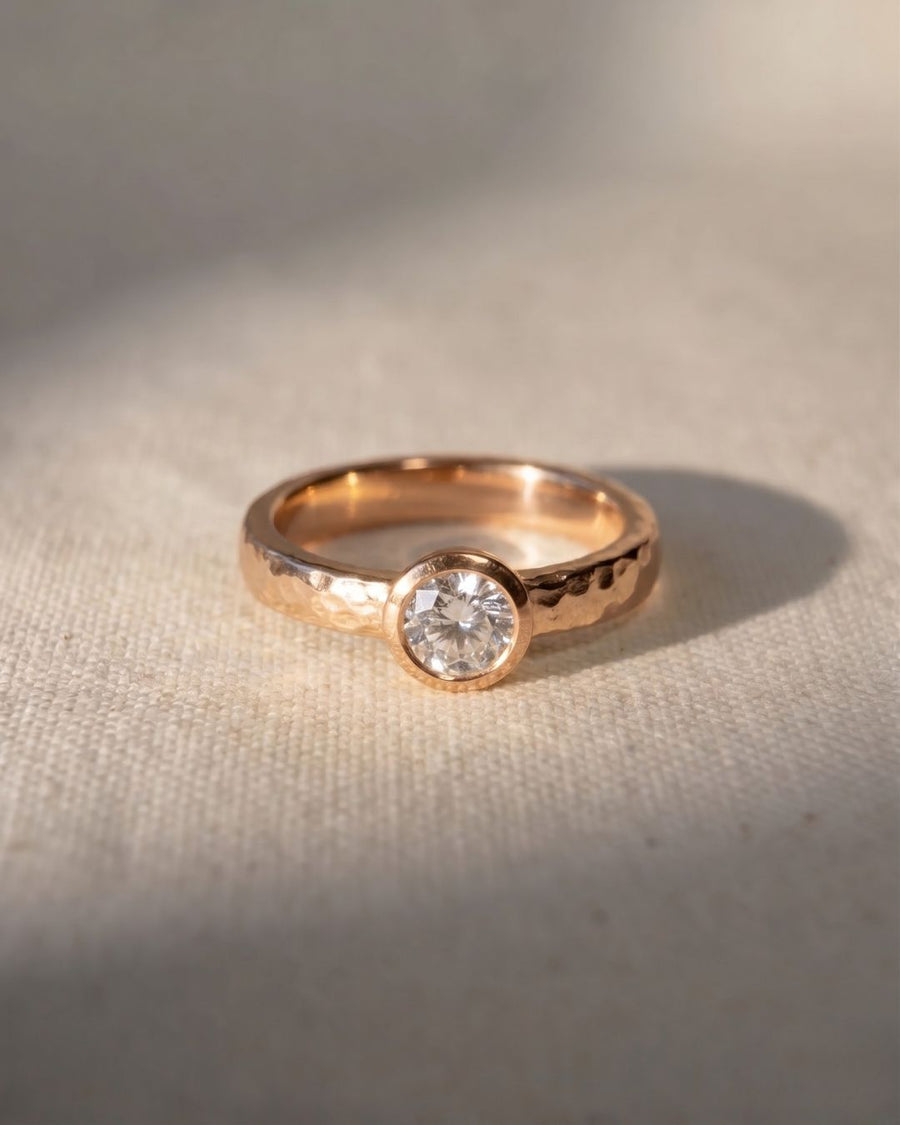 Rose gold hammered ring with a round brilliant cut diamond.