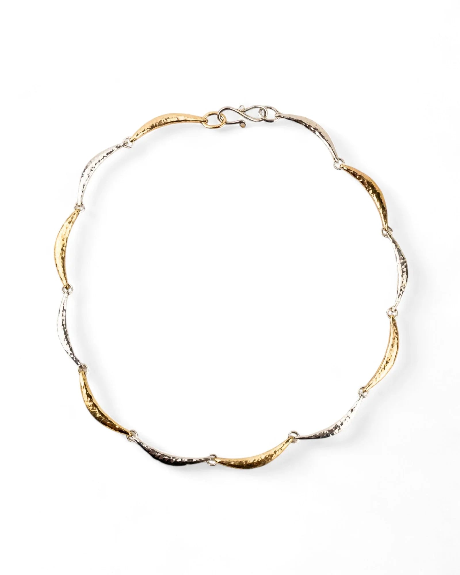 Hammered silver and gold crescent necklace with textured finish on white background