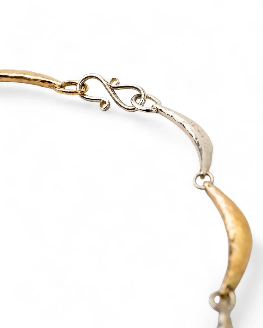 Hammered silver and gold crescent necklace with textured metal and organic shapes