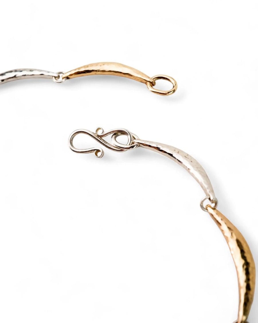 Hammered silver and gold crescent necklace with textured finish on white background