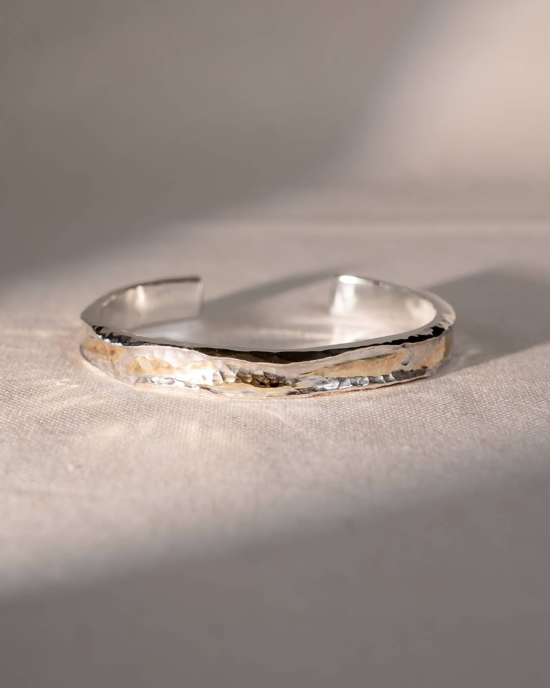 Hammered silver and gold cuff bangle with a textured finish.