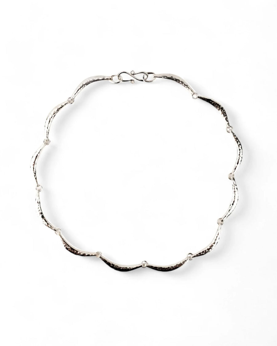 Hammered silver crescent necklace with organic, textured links on a white background