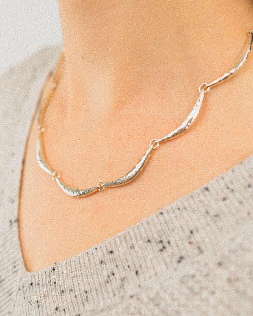 Handmade hammered silver crescent necklace with organic shapes worn on neck
