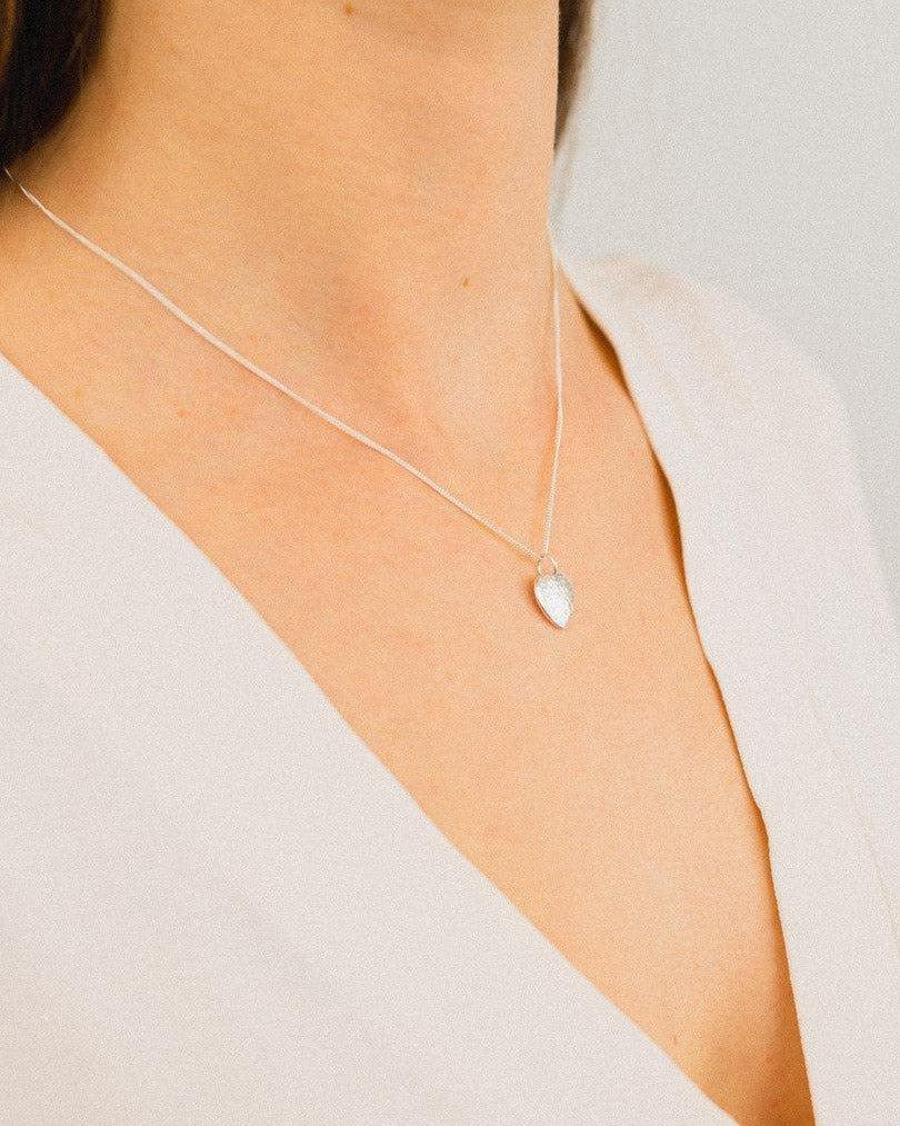 Woman wearing a hammered silver heart pendant necklace on a fine chain