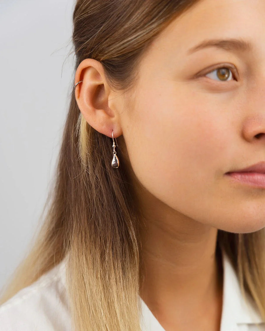 Woman wearing hammered silver teardrop dangly earring, organic handmade jewelry