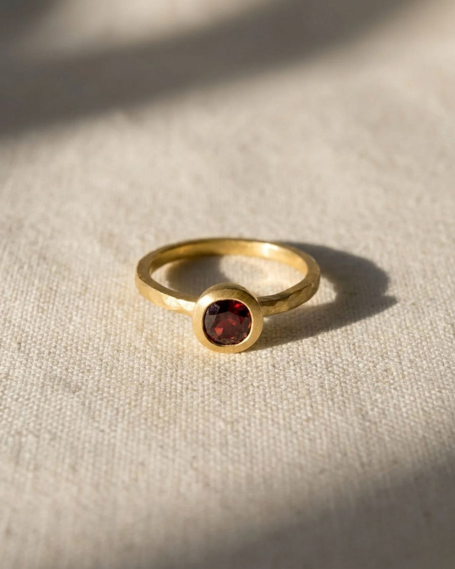 Hammered yellow gold ring with a round ruby gemstone.