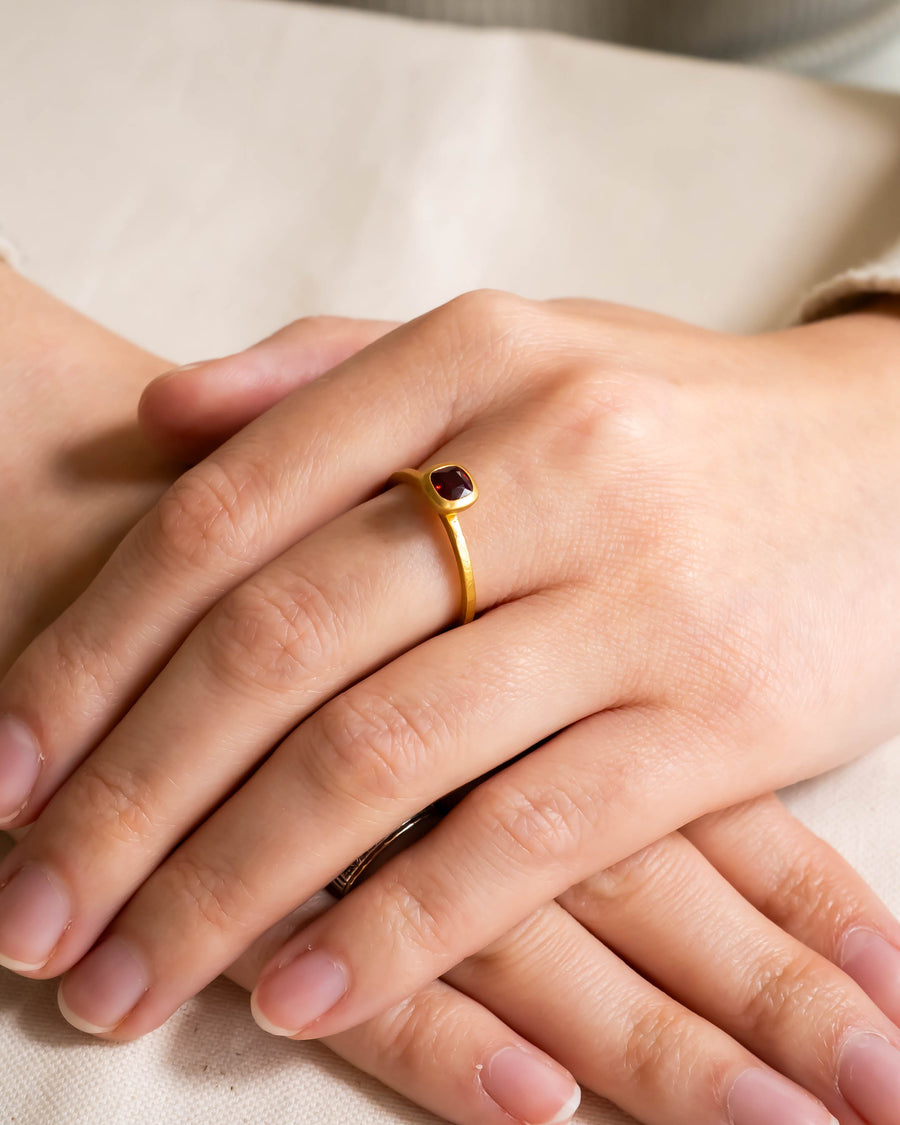 Hammered yellow gold ruby ring on a hand.